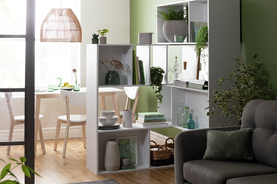 A Habitat extendable wide white shelving unit used as a room divider in a living room.